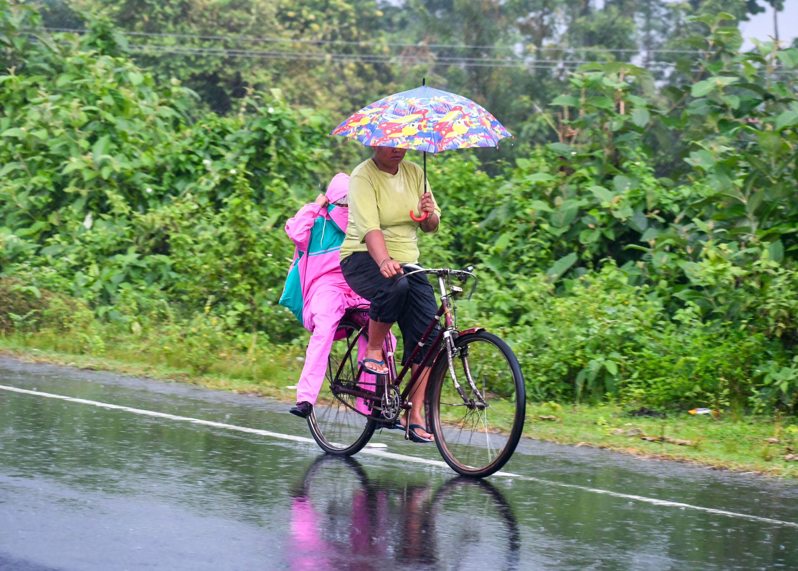 Jalpaiguri: Woman cycles with children in rain #Gallery Jalpaiguri: Woman cycles with children in rain #Gallery
