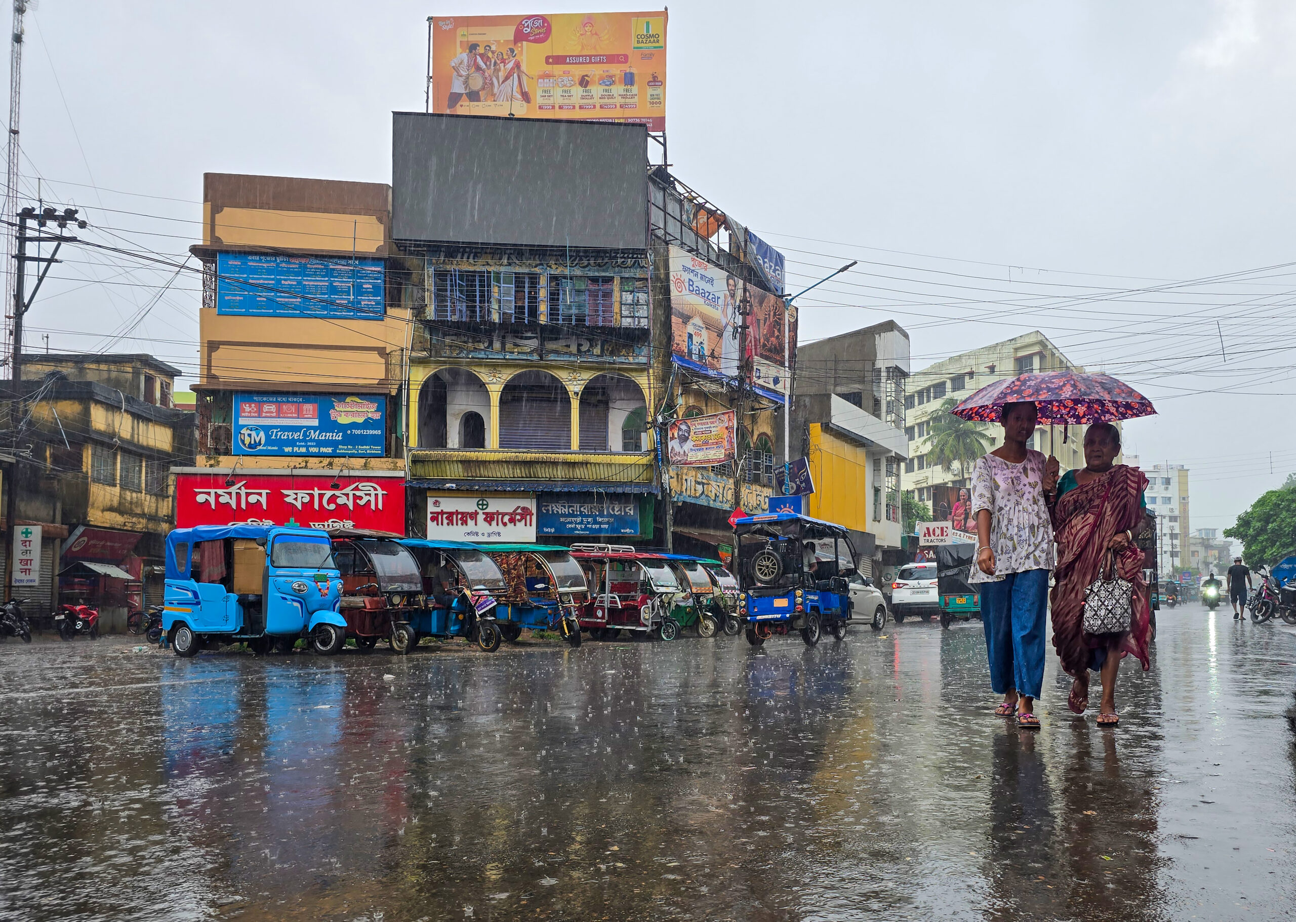 Suri: Commuters walk with umbrellas as vehicles move along a rain-soaked road near Suri Bus Stand in Birbhum district of West Bengal on Sunday, September 20, 2026. (Photo: IANS)